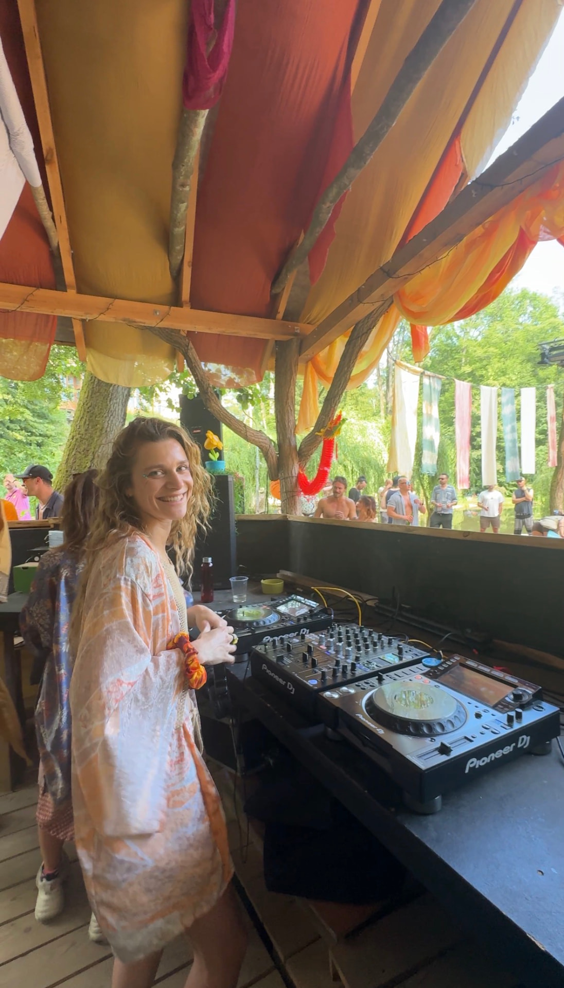 Clé smiling behind the decks at a daytime festival set