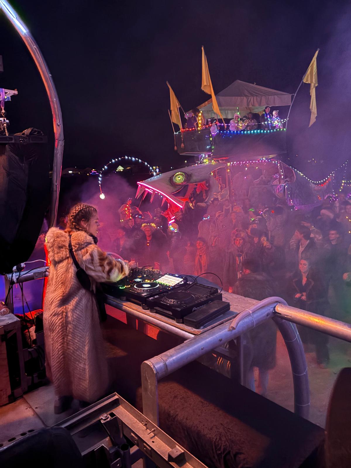 Clé DJing at night atop a decorated festival art car